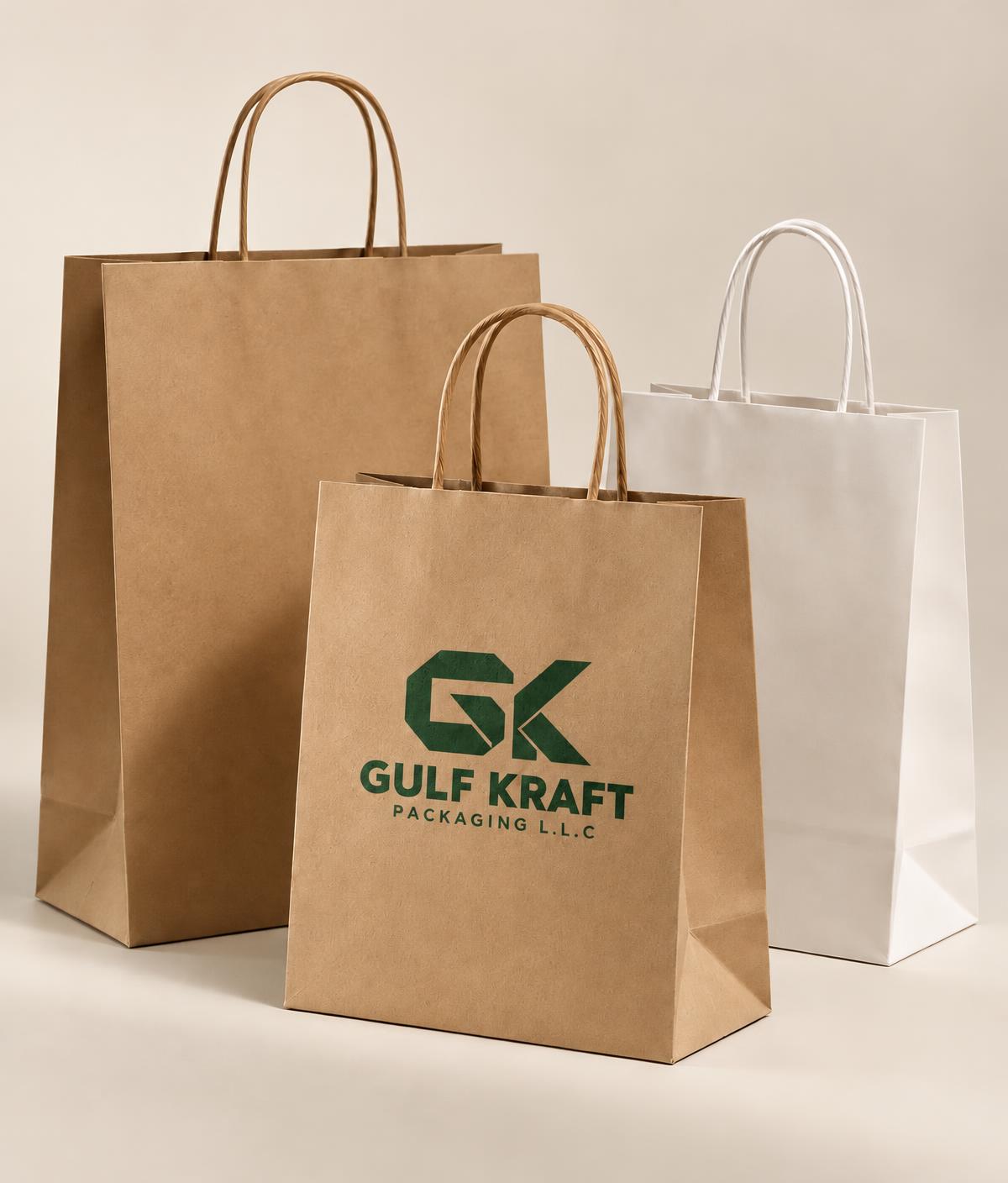 Kraft and white paper bags with twisted paper handles, one printed with the GK mark